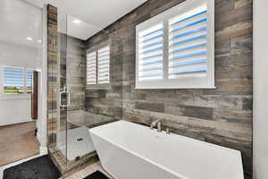 Bathroom with a freestanding tub, a shower stall, recessed lighting, and wood walls