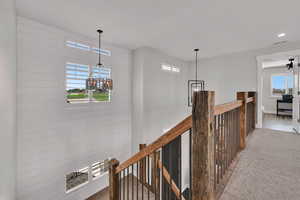 Corridor featuring an upstairs landing, carpet flooring, and a chandelier