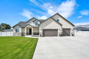 Modern farmhouse with board and batten siding, a gate, a garage, driveway, and a porch
