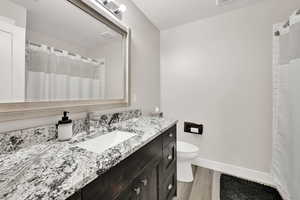 Full bath with wood finished floors, vanity, a textured ceiling, and a shower with shower curtain