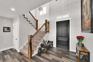 Foyer featuring dark wood finished floors, a high ceiling, stairway, recessed lighting, and a chandelier