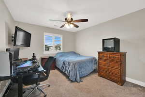 Carpeted bedroom with a desk and ceiling fan