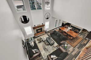 Living room featuring a towering ceiling, a stone fireplace, and wood finished floors