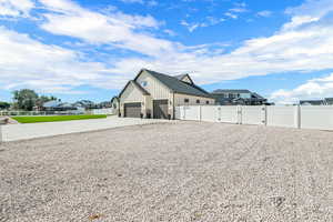 View of side of property with a gate, board and batten siding, concrete driveway, and a residential view
