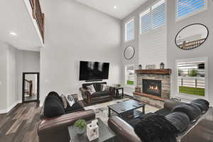 Living area featuring a high ceiling, dark wood-type flooring, recessed lighting, and a stone fireplace