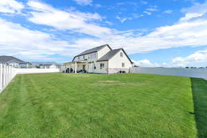 Rear view of house featuring a fenced backyard, stone siding, and a mountain view