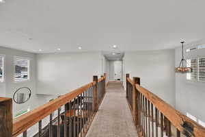 Hallway featuring plenty of natural light, an upstairs landing, carpet floors, a chandelier, and recessed lighting