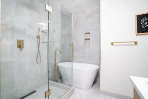 Full bath with a freestanding tub, a stall shower, vanity, and tile walls