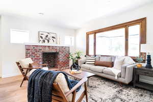 Living room featuring light wood-style flooring, a brick fireplace, and recessed lighting
