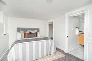 Carpeted bedroom with a textured ceiling and marble look tile flooring