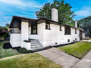 View of home's exterior featuring a lawn and a chimney