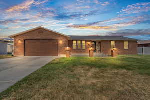 Ranch-style house with brick siding, an attached garage, concrete driveway, and a front yard