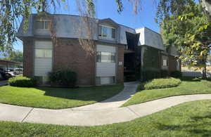 View of front facade featuring brick siding, a balcony, a front lawn, and mansard roof