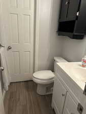 Half bathroom with dark wood-style floors and vanity