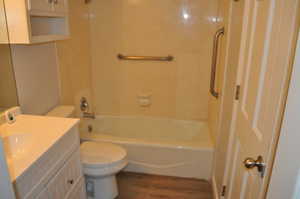 Bathroom featuring tub / shower combination, vanity, and dark wood finished floors