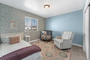 Carpeted bedroom featuring wallpapered walls and a closet