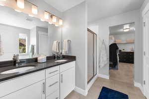 Full bathroom with double vanity, a stall shower, tile patterned floors, and a spacious closet