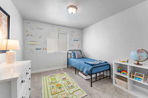Bedroom with light carpet and a textured ceiling