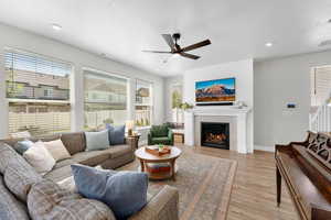Living area featuring a ceiling fan, light wood-style floors, a lit fireplace, recessed lighting, and a textured ceiling