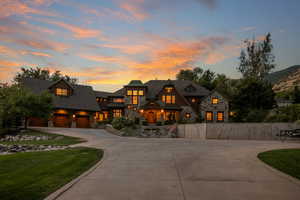 View of front of property featuring stone siding, curved driveway, and a lawn