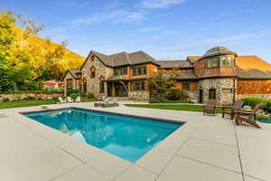 Outdoor pool with a patio area, a diving board, and a yard