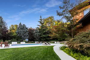 View of green lawn with an outdoor pool and a patio