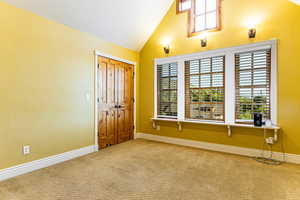 Entryway featuring healthy amount of natural light, carpet floors, vaulted ceiling, and a textured wall