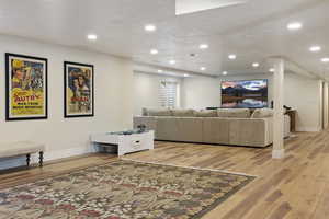 Living room featuring light wood-style flooring, baseboards, recessed lighting, and a textured ceiling