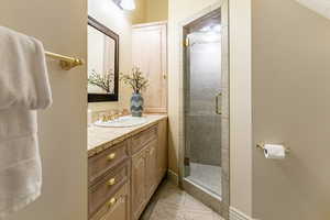 Bathroom featuring a stall shower, vanity, and light tile patterned flooring