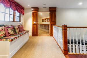 Hall with a textured wall, light colored carpet, and recessed lighting