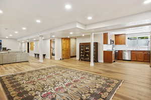Living area with light wood-style floors, bar with sink, baseboards, and recessed lighting