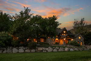 Back of house featuring stone siding and a lawn