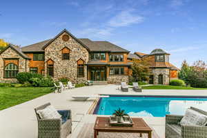 Back of house with an outdoor living space, stone siding, and a lawn