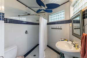 Full bathroom featuring tile walls, a shower stall, tile patterned flooring, and a ceiling fan