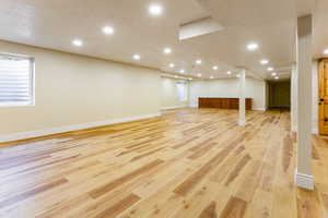 Basement featuring recessed lighting, a textured ceiling, and light wood-style floors