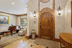 Entryway with recessed lighting, wood finished floors, baseboards, and crown molding