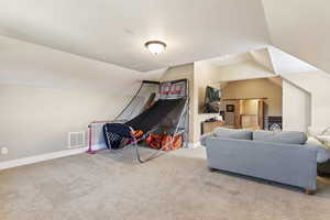 Living room featuring vaulted ceiling, carpet floors, and baseboards