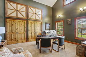 Office with high vaulted ceiling, carpet floors, healthy amount of natural light, and baseboards