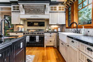 Kitchen with cream cabinetry, dark cabinets, double oven range, and light wood finished floors