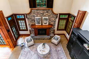 Living room featuring a towering ceiling, a fireplace, a textured wall, and wood finished floors