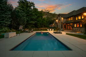 Pool at dusk with french doors, a patio area, and an outdoor pool