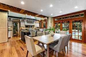 Dining space featuring beamed ceiling, recessed lighting, light wood-type flooring, a textured ceiling, and french doors