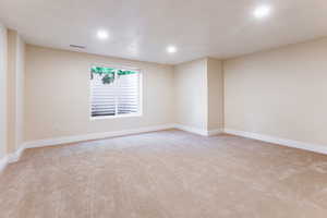 Empty room with light carpet and recessed lighting