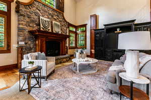 Living area featuring a fireplace, a textured wall, a high ceiling, and light wood-style flooring