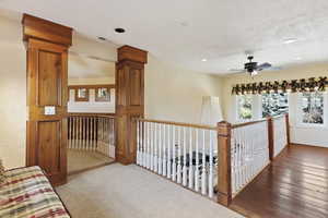 Hall with an upstairs landing, recessed lighting, a textured wall, a textured ceiling, and hardwood / wood-style floors