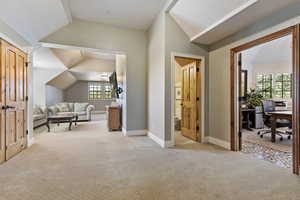 Bedroom featuring lofted ceiling, light colored carpet, an office area, and baseboards