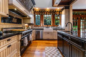 Kitchen featuring premium stove, light wood-style floors, custom exhaust hood, stainless steel dishwasher, and decorative backsplash