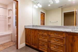 Bathroom featuring dark tile patterned flooring, double vanity,  shower combination, and recessed lighting
