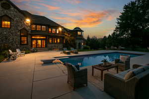 Pool at dusk with an outdoor pool, a diving board, french doors, and a patio