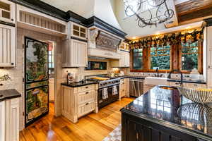 Kitchen featuring light wood finished floors, double oven range, tasteful backsplash, dishwasher, and glass insert cabinets